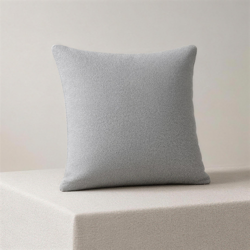 The Case in ash, a square cushion cover in one flat pale grey, standing upright on a plinth.