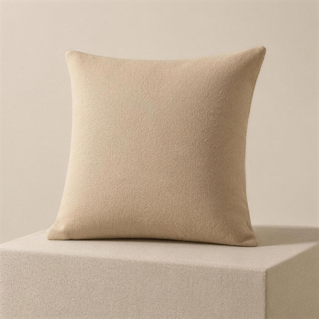 The Case in bone, a square cushion cover in one flat warm off-white, standing upright on a plinth.